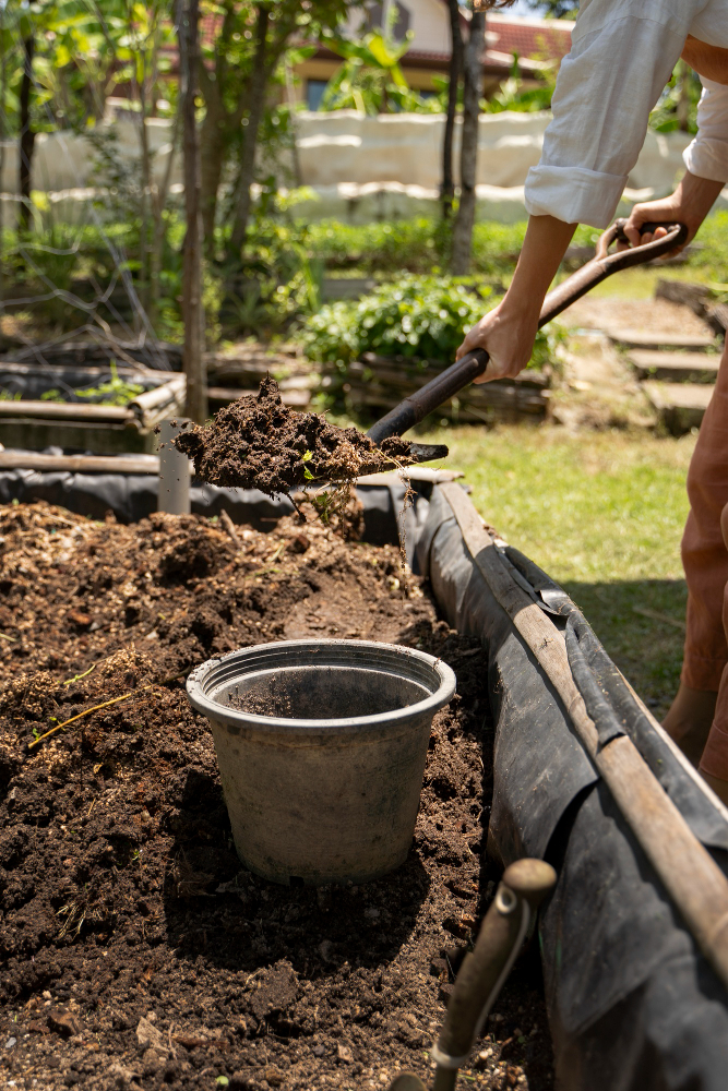 Landscaper shaping soil for proper grading and drainage in garden design